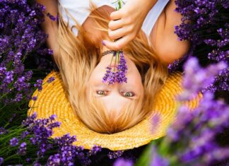 Beautiful woman with blond hair is lying down in lavender flower