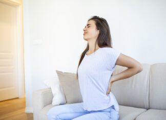 Nejlepší bylinky při akutní bolesti zad Woman suffering from backache at home. Lower Back Pain . Woman feels back pain massaging aching muscles, sad woman suffers from low back